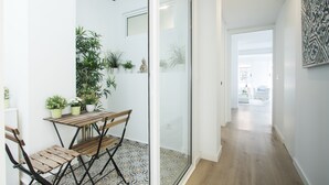 A modern interior with a wooden table and chairs, potted plants, and a glass door leading to a hallway. - Spacious 4BR Apartment, Walk to Beach (Alacant)