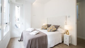 A modern bedroom with a large bed, bedside tables, and a window. - Spacious 4BR Apartment, Walk to Beach (Alacant)