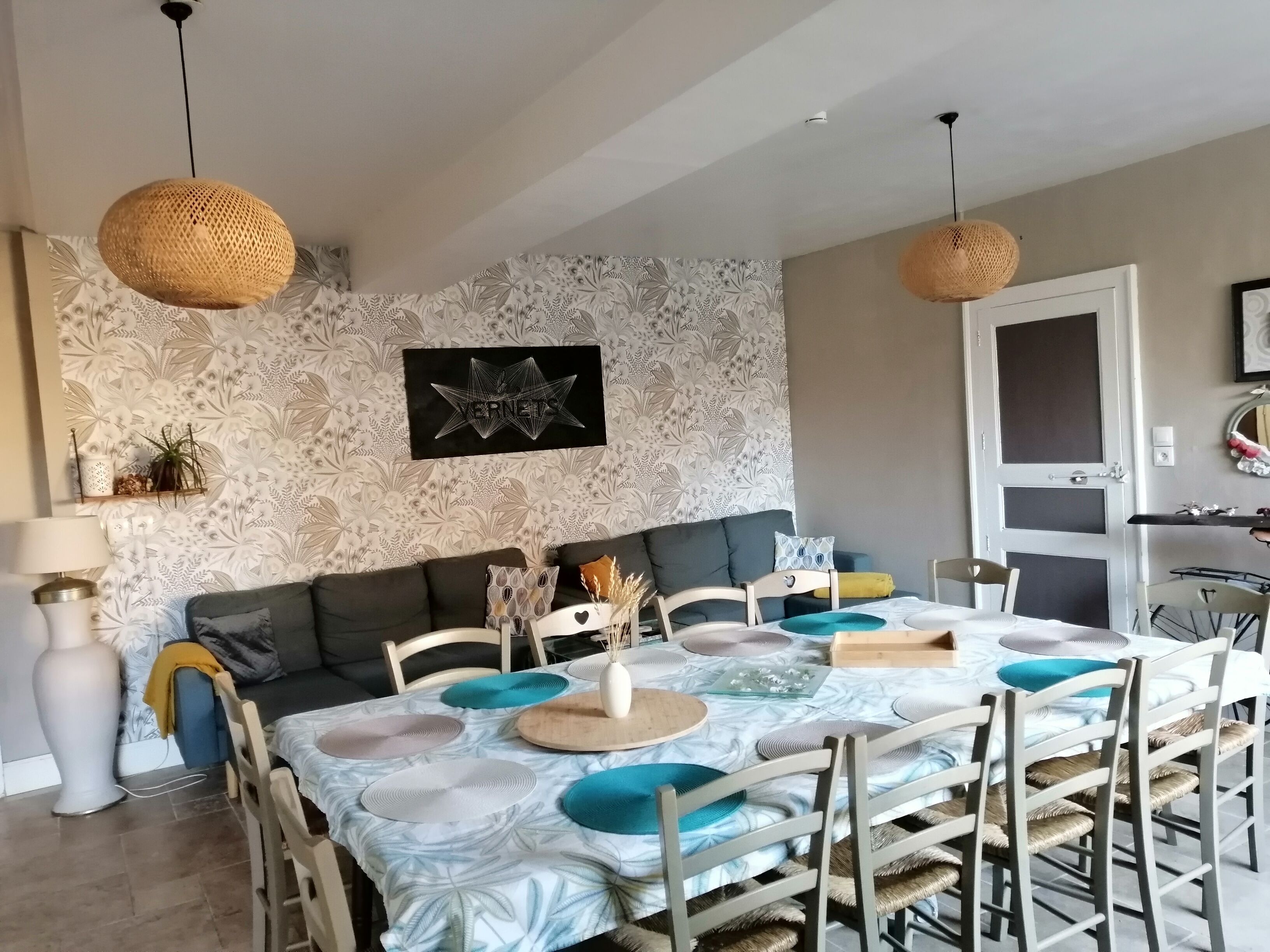 Un coin repas avec une table ronde, des chaises et une nappe à motifs.