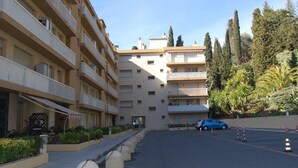 A multi-story hotel with balconies, a parking area, and surrounding greenery. - Top-floor 2-room with air con & private parking in Menton (Menton)