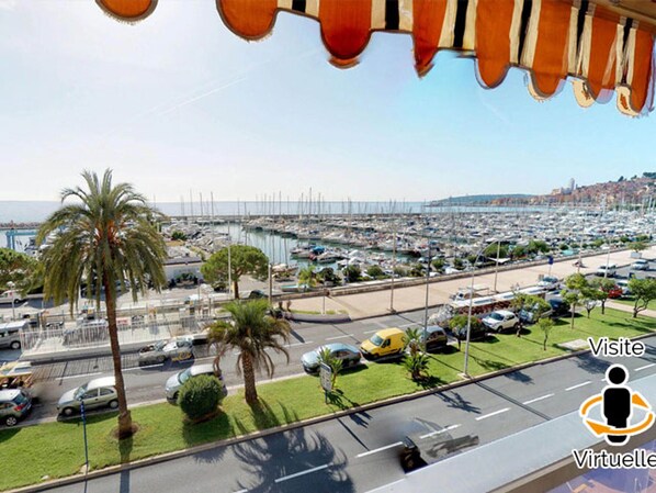 A marina with numerous boats docked, a parking area with cars, and a view of the coastline. - Renovated sea-facing studio with terrace in Menton (Menton)
