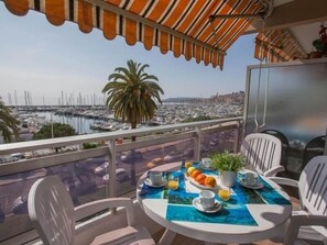 A balcony with a table set for two, overlooking a marina with boats and a cityscape. - Renovated sea-facing studio with terrace in Menton (Menton)