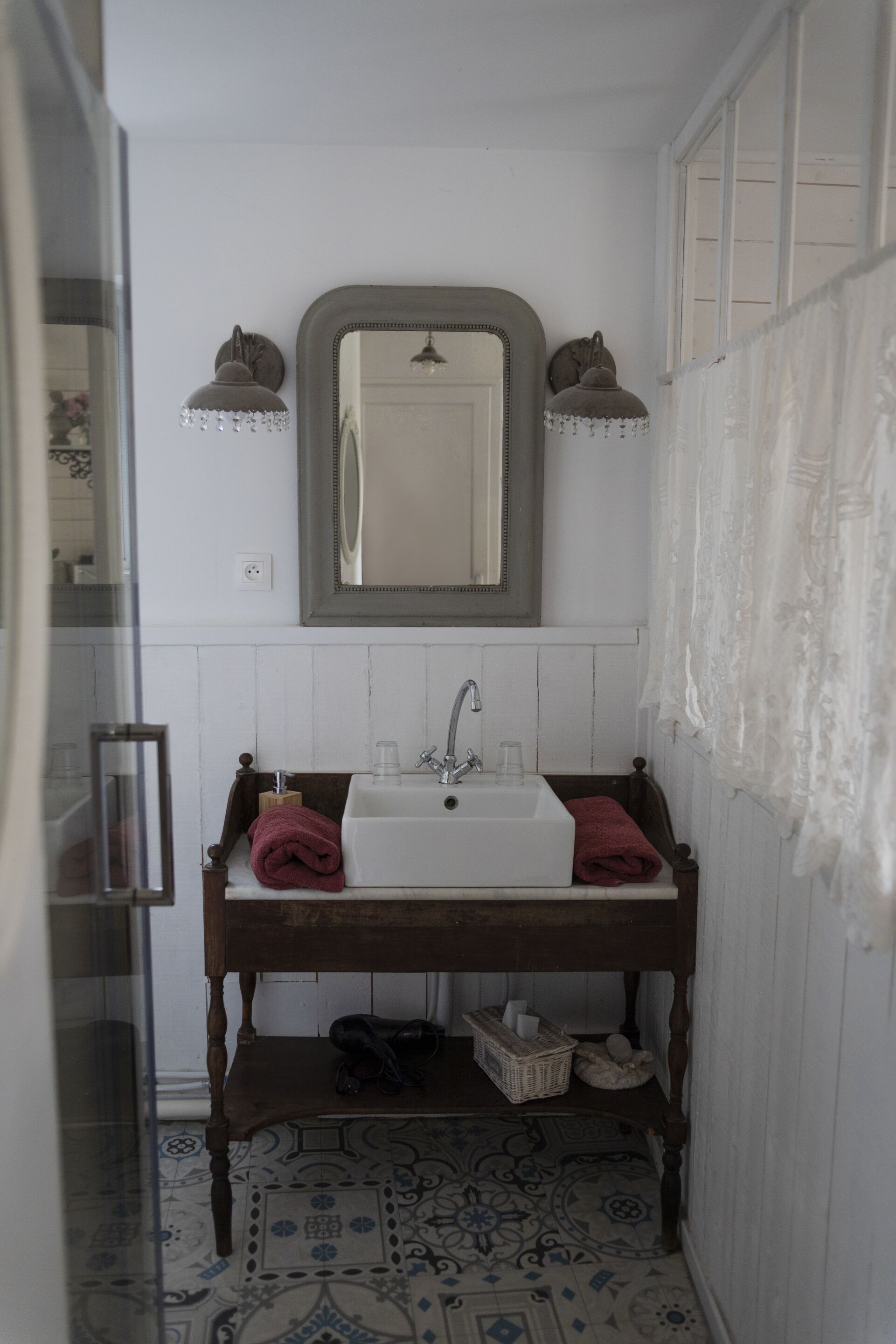 Une salle de bain avec un lavabo blanc, un meuble-lavabo en bois et un miroir au-dessus.