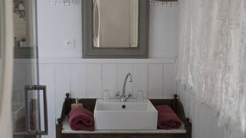Un bagno con un lavandino bianco, un mobile contenitore in legno e uno specchio sopra.