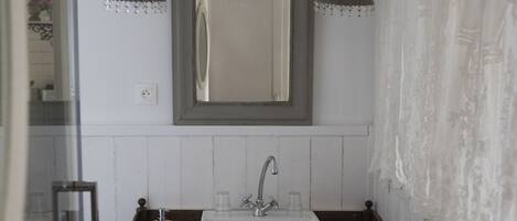 Un baño con lavamanos blanco, tocador de madera y un espejo arriba.