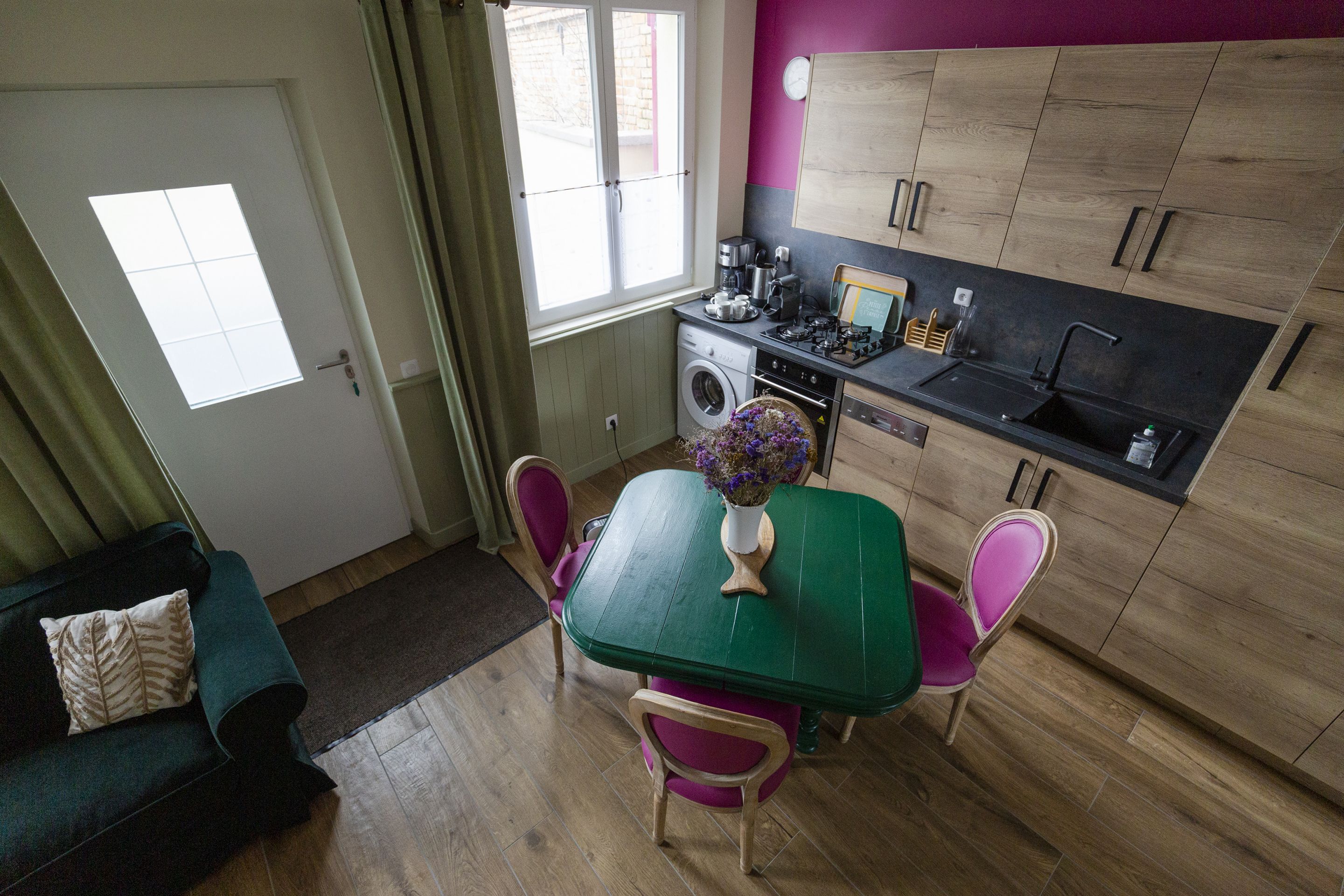 Une cuisine compacte comprenant une table à manger, des chaises, un lave-linge et une fenêtre.