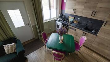 Une cuisine compacte comprenant une table à manger, des chaises, un lave-linge et une fenêtre.