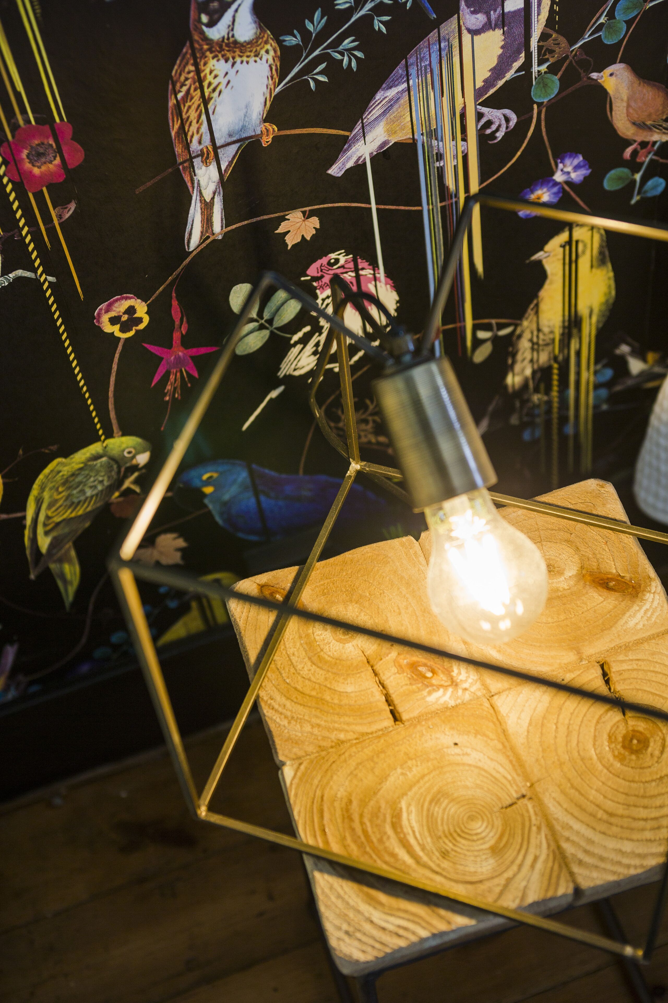 A geometric metal frame with a light bulb, surrounded by a wooden surface with visible grain patterns.