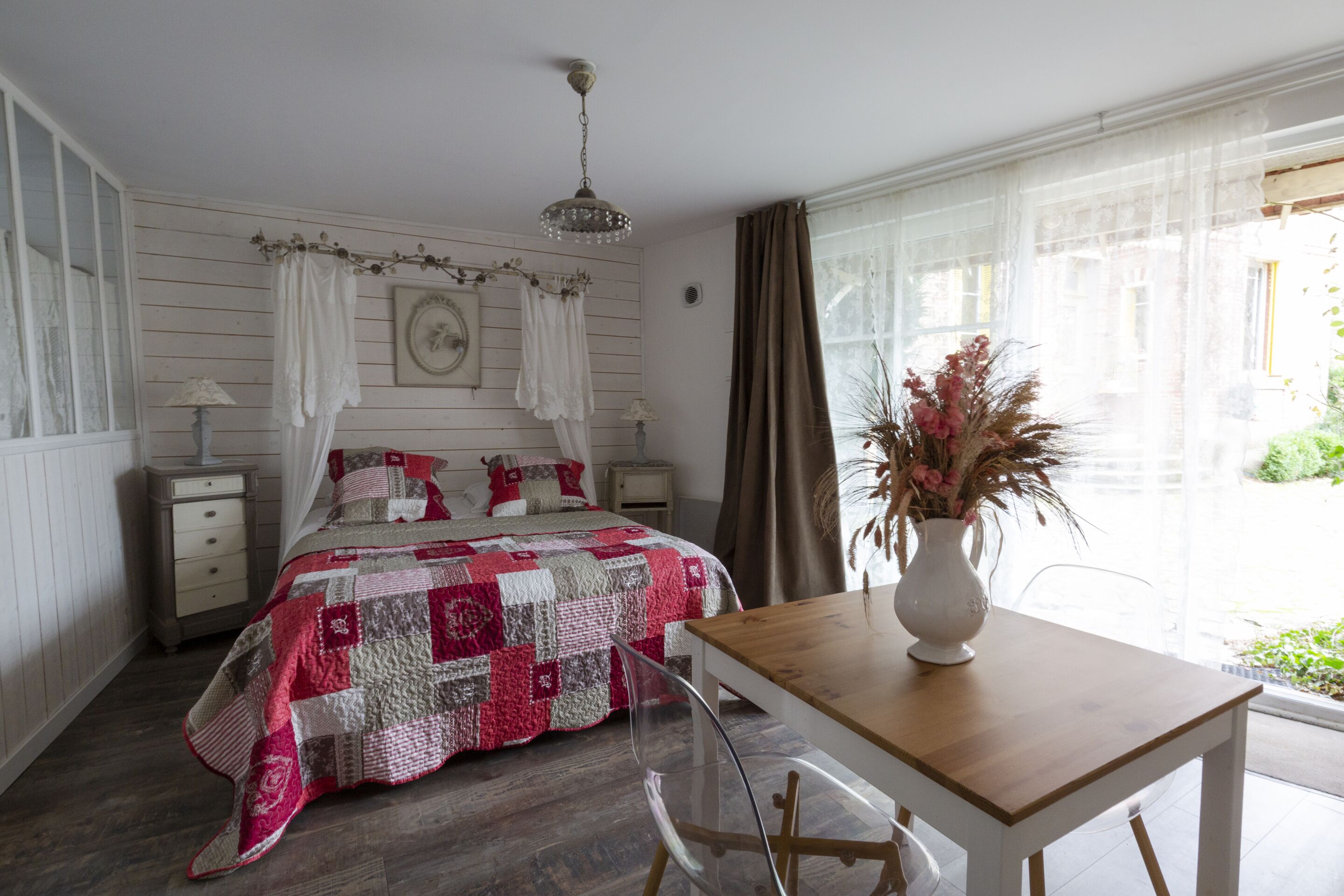 Un dormitorio con cama, mesita de noche, mesa y ventana.