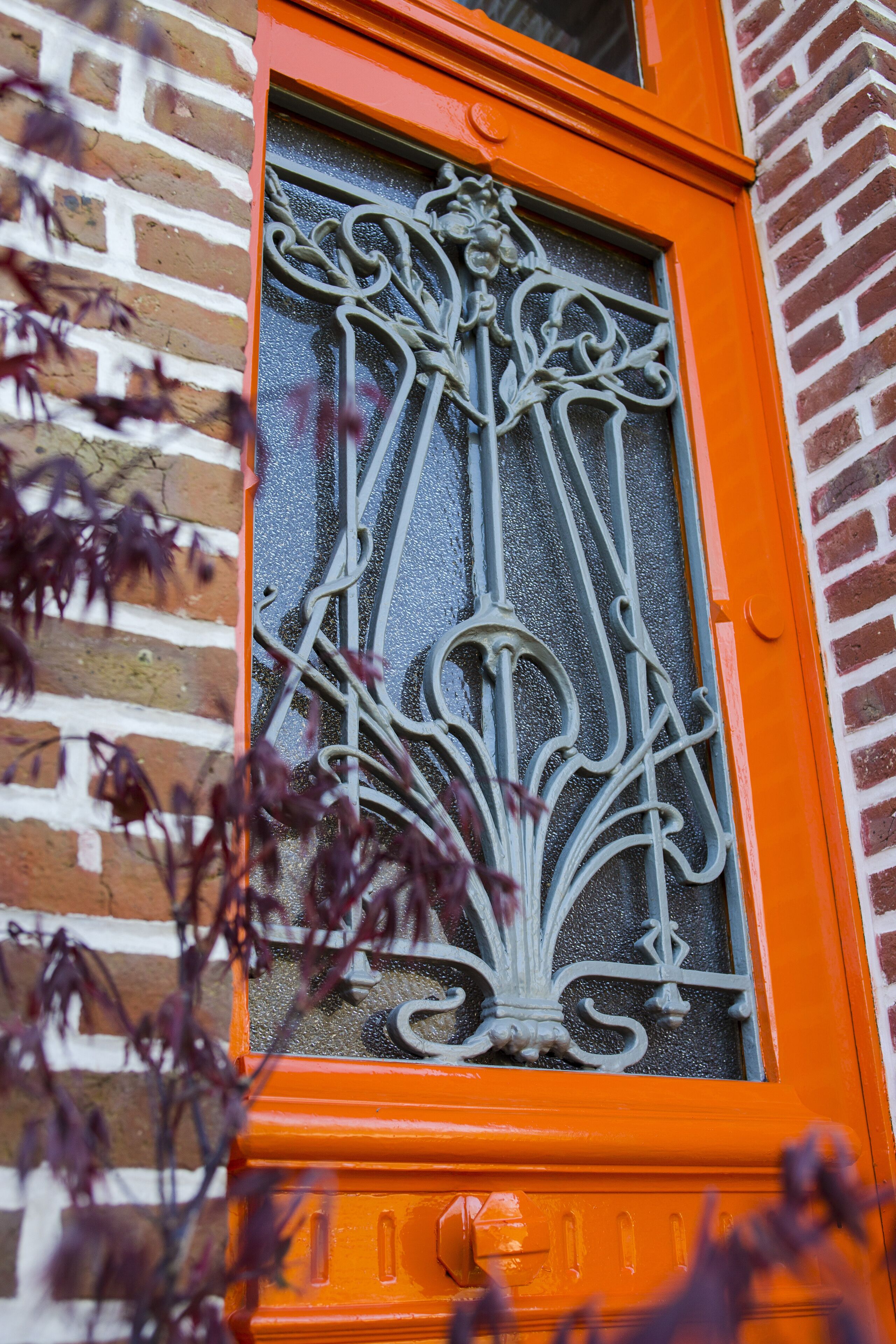 Une fenêtre ornée de motifs métalliques et dotée d’un cadre orange.