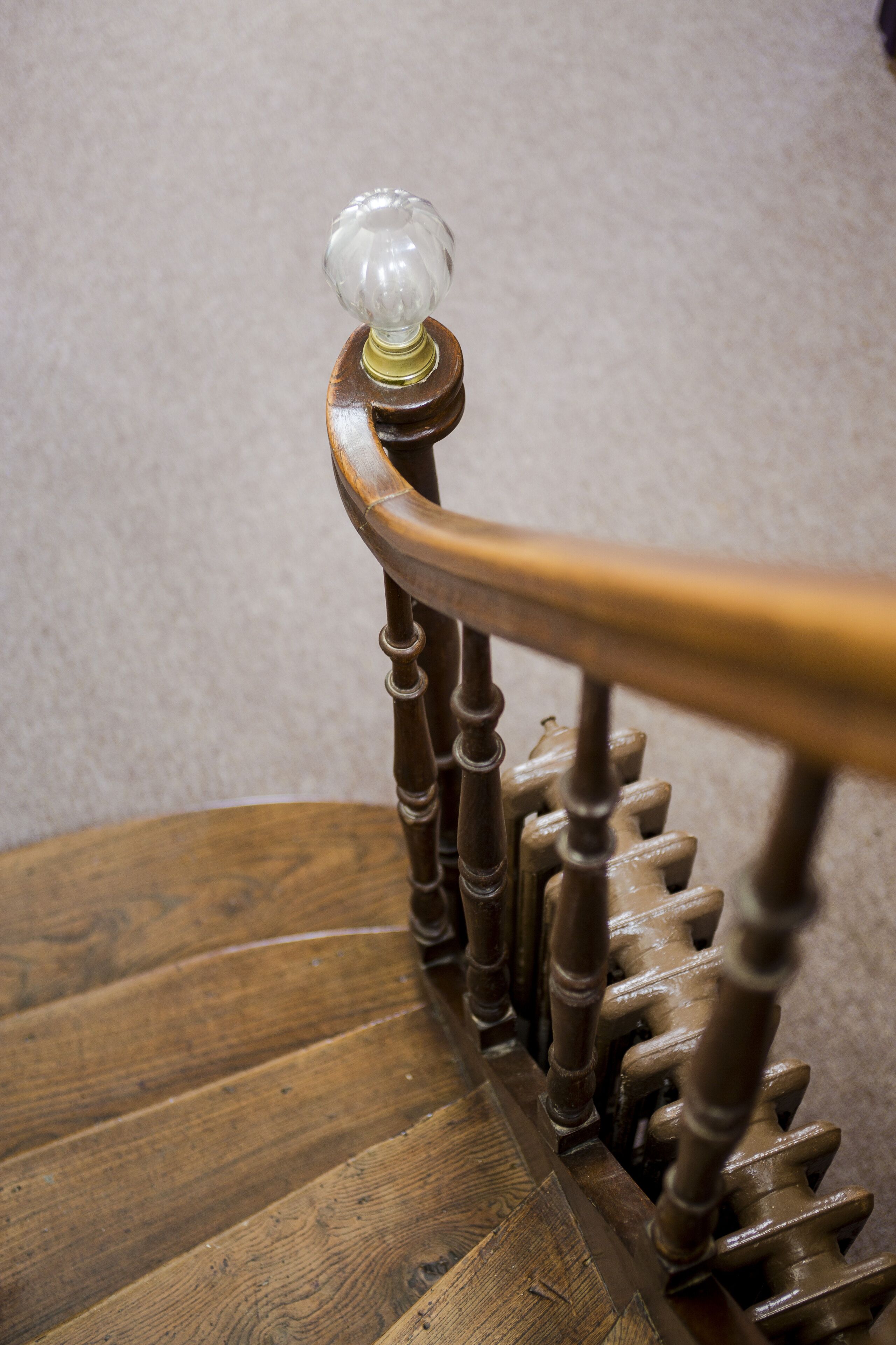 A wooden staircase with a glass ball on the top of the handrail.