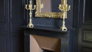 A black fireplace with a gold-framed mirror above it.
