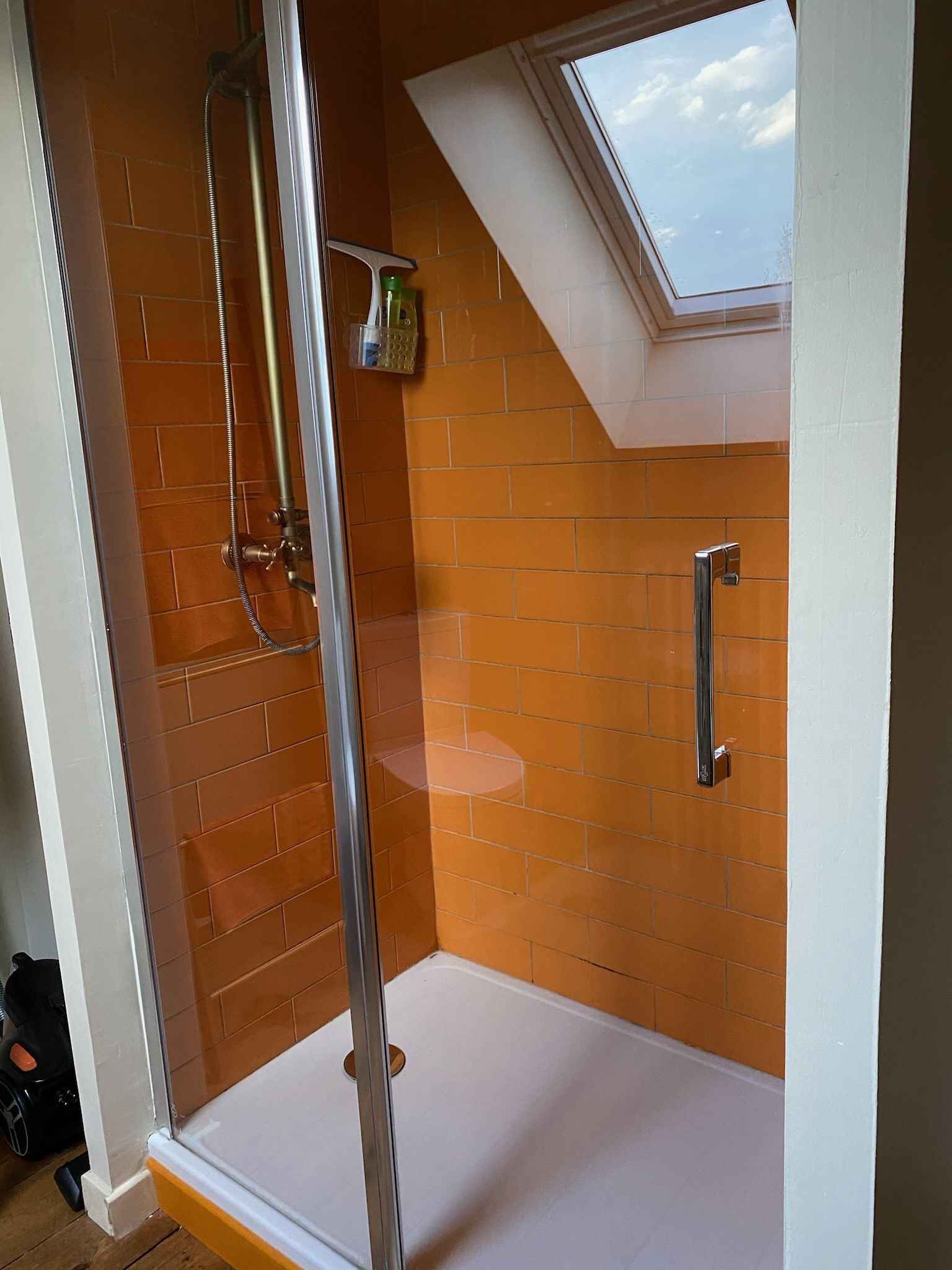 Eine Dusche mit Glastür, eine weiße Badewanne und ein Oberlicht.