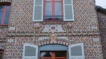 Un bâtiment à la façade en briques, doté de nombreuses fenêtres avec volets et d’éléments décoratifs.