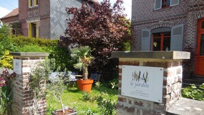 Een tuin met plantenpotten en een bordje met de tekst 'le jardin'.