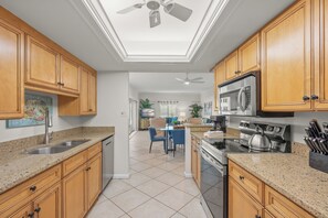 A kitchen with wooden cabinets, a stainless steel sink, a microwave, and a stove. - Island House Beach Resort 2S (Siesta Key)