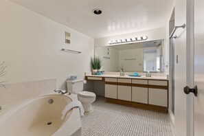 A bathroom with a bathtub, toilet, sink, and mirror.