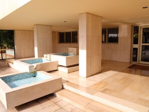 A modern spa area with multiple hot tubs and a tiled floor.
