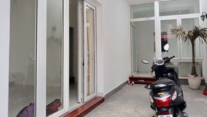 Un interior moderno con un portón de cristal corredera que da a un balcón, una moto estacionada y una planta en maceta.