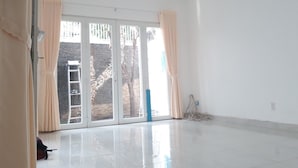 Una habitación amplia con un gran ventanal corredero que da a un espacio exterior, un ventilador de techo y un equipo de aire acondicionado.
