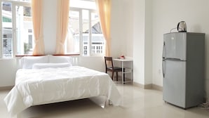 Un dormitorio con una cama, un escritorio y un refrigerador.