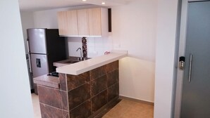 Uma cozinha compacta com uma ilha integrada, geladeira e armário.