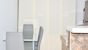 Quarto de hotel moderno com divisória de vidro, bancada de mármore e poltrona estofada cinza.