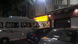 A parked bus and cars in front of a building with a sign that reads "Royal Rosi Restaurant".