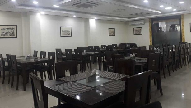 A conference room with multiple tables and chairs, ceiling lights, and framed pictures on the walls.