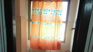 A small bathroom with a toilet, sink, and window with a curtain.