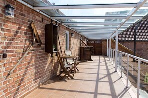 Een overdekte patio met bakstenen muren, een glazen dak en een betegelde vloer.