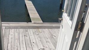 A wooden dock leading to a body of water, with a white door and window visible on the right.