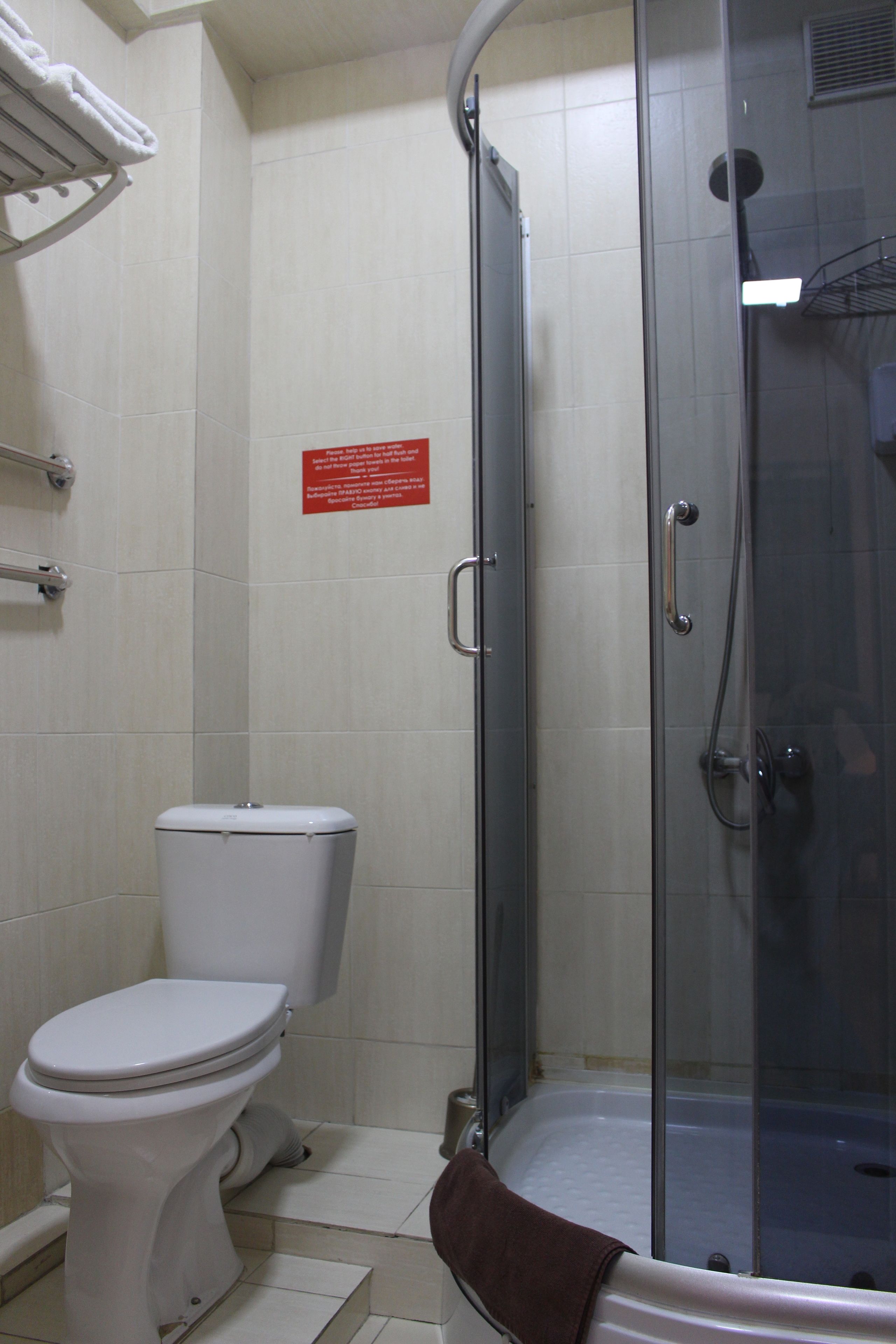 A bathroom with a toilet, a glass-enclosed shower, and a towel rack.