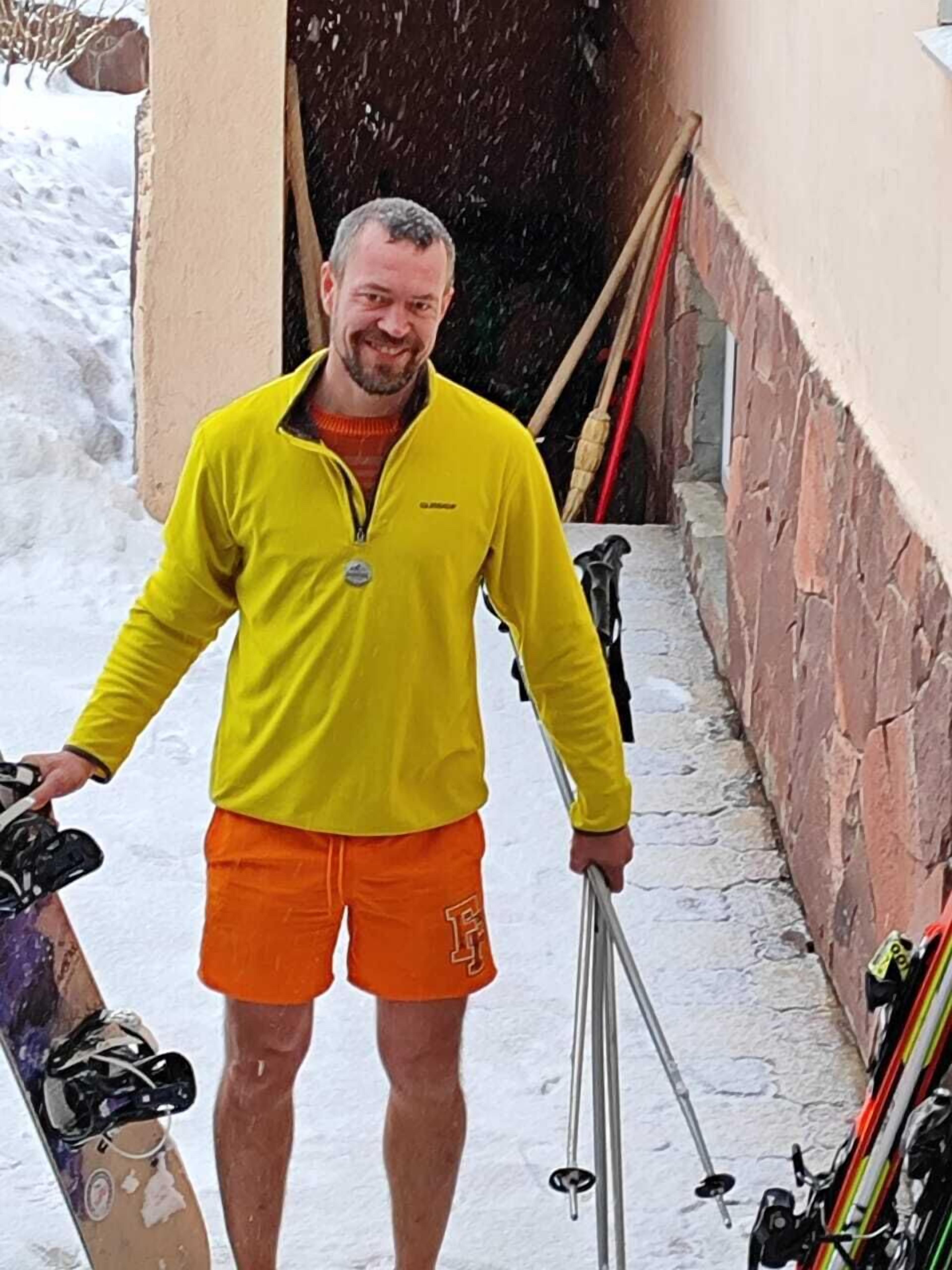A person standing in a snowy outdoor area with a snowboard and ski poles.