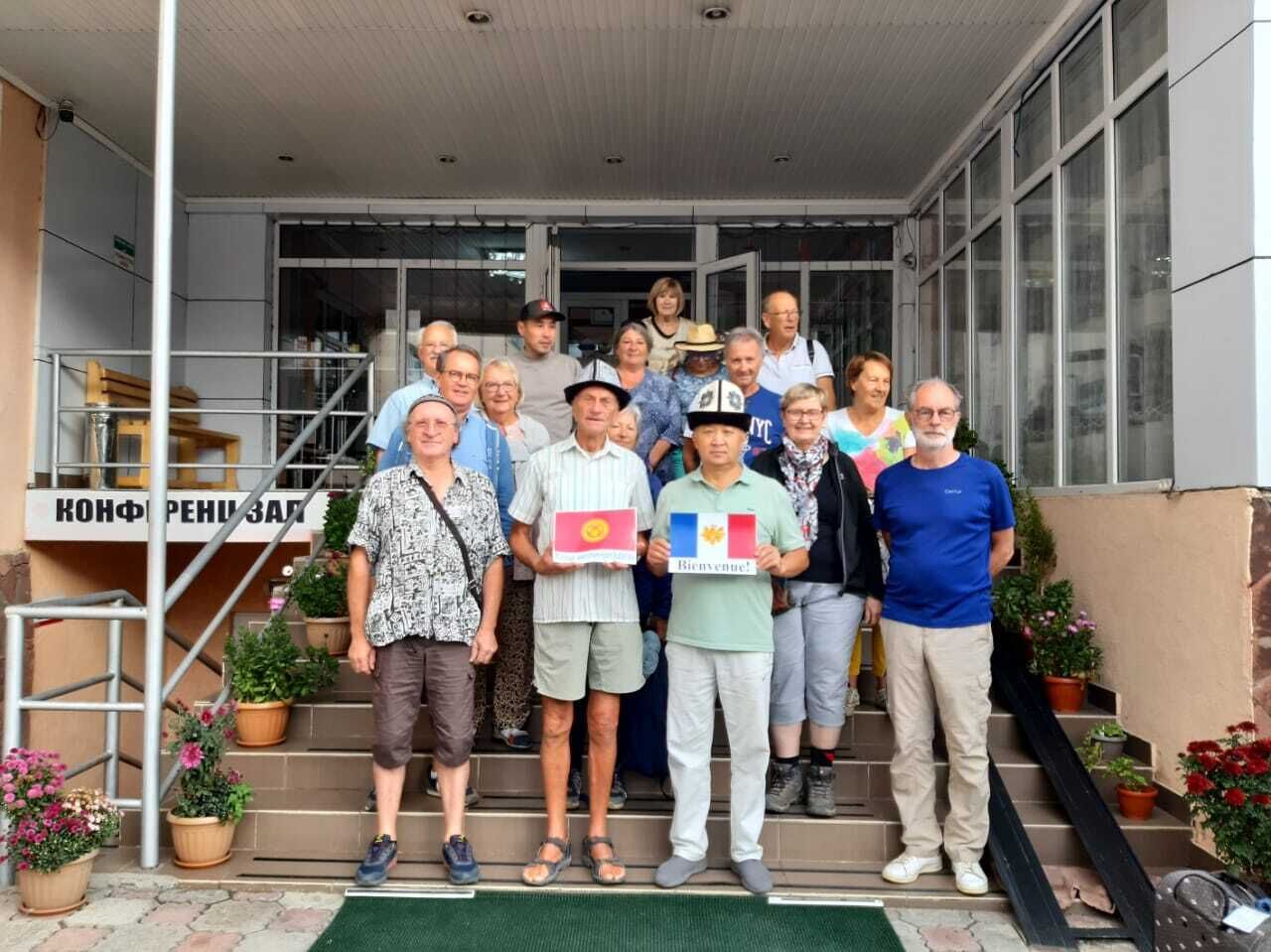 Un gruppo di persone in piedi su una scala antistante un edificio con un cartello che recita 'KONFRESEHUS'.