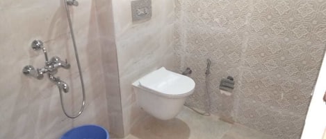Un baño con inodoro blanco, ducha y lavamanos azul.