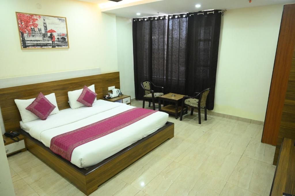 A hotel room with a bed, bedside table, chair, and a small desk with a chair.