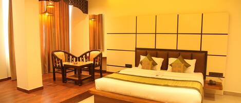 A bedroom with a large bed, a wooden bench, and a desk.