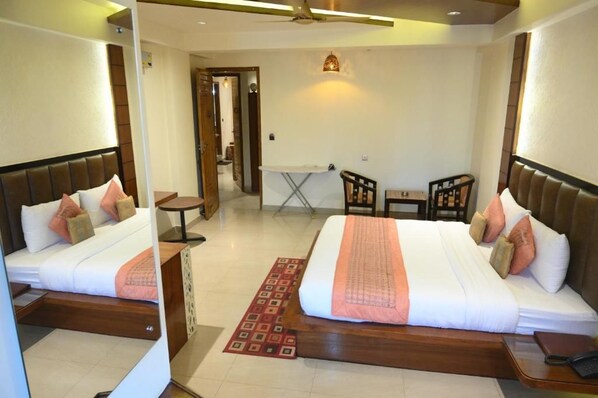 Habitación de hotel con dos camas, una mesita y una silla.