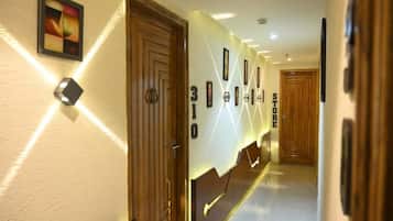 Un pasillo de hotel con puertas de madera, una obra de arte colgada en la pared y una serie de números enmarcados.