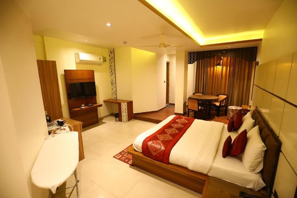 A hotel room with a bed, a desk, a chair, a television, and a small table.