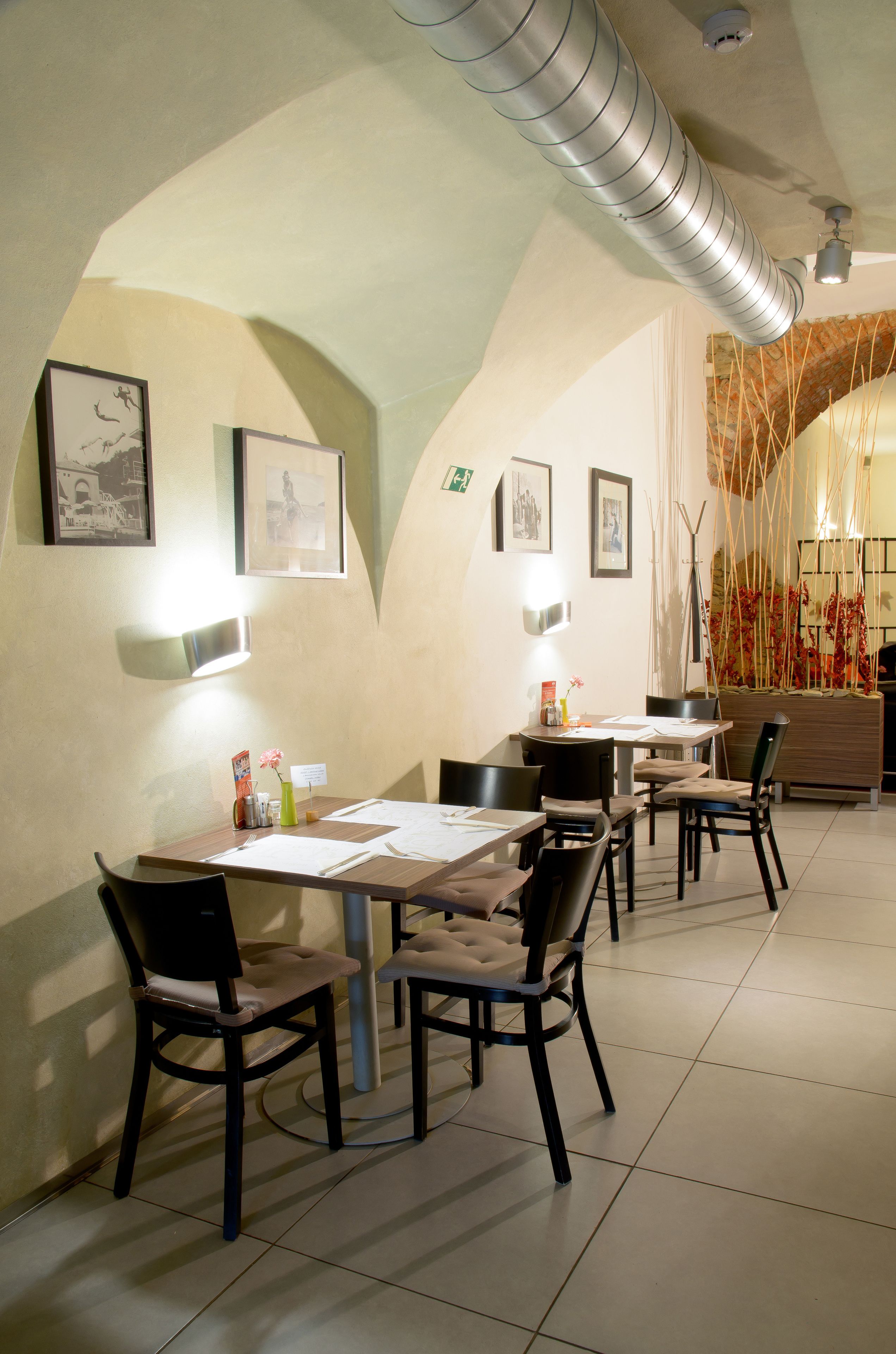 A dining area with a high ceiling, exposed ductwork, and framed pictures on the walls.