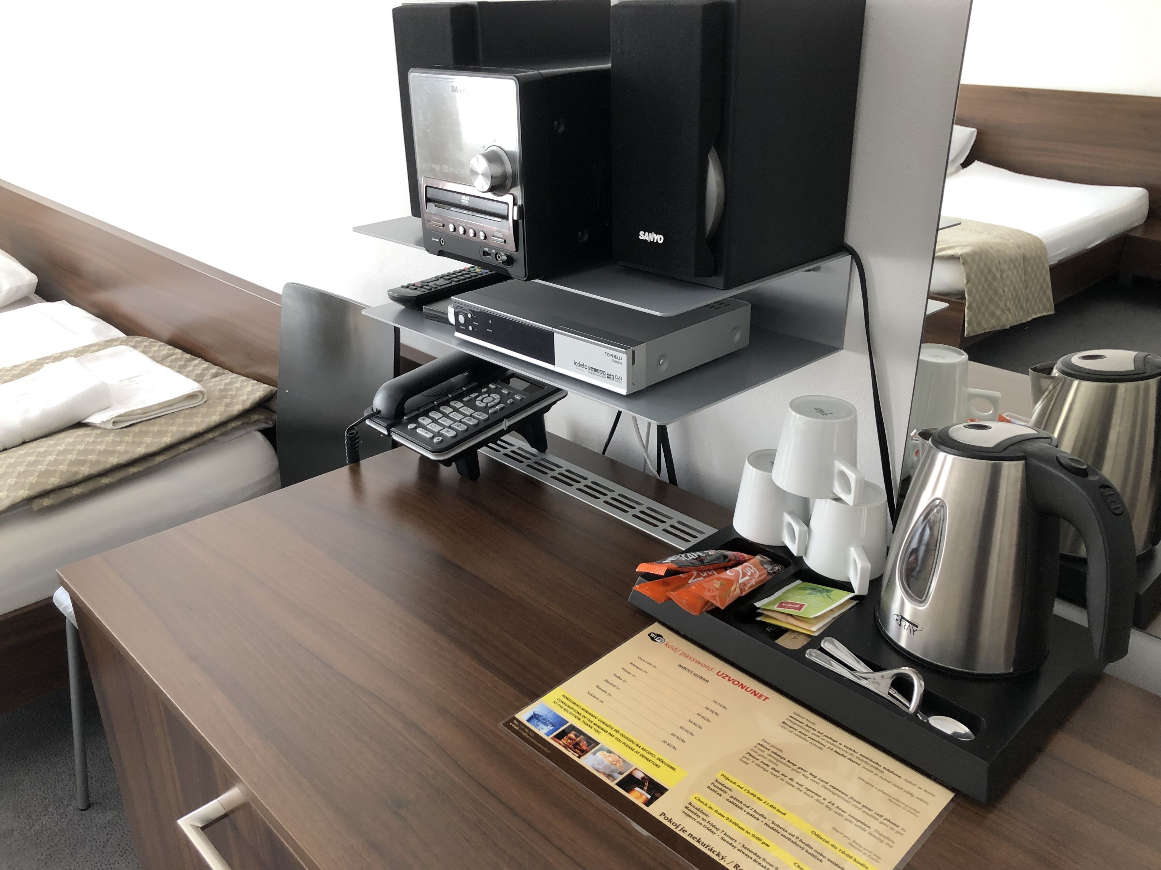 Une chambre d’hôtel équipée d’un bureau, d’une machine à café, d’un téléphone, d’une bouilloire et d’un menu.