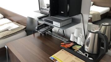 Une chambre d’hôtel équipée d’un bureau, d’une machine à café, d’un téléphone, d’une bouilloire et d’un menu.