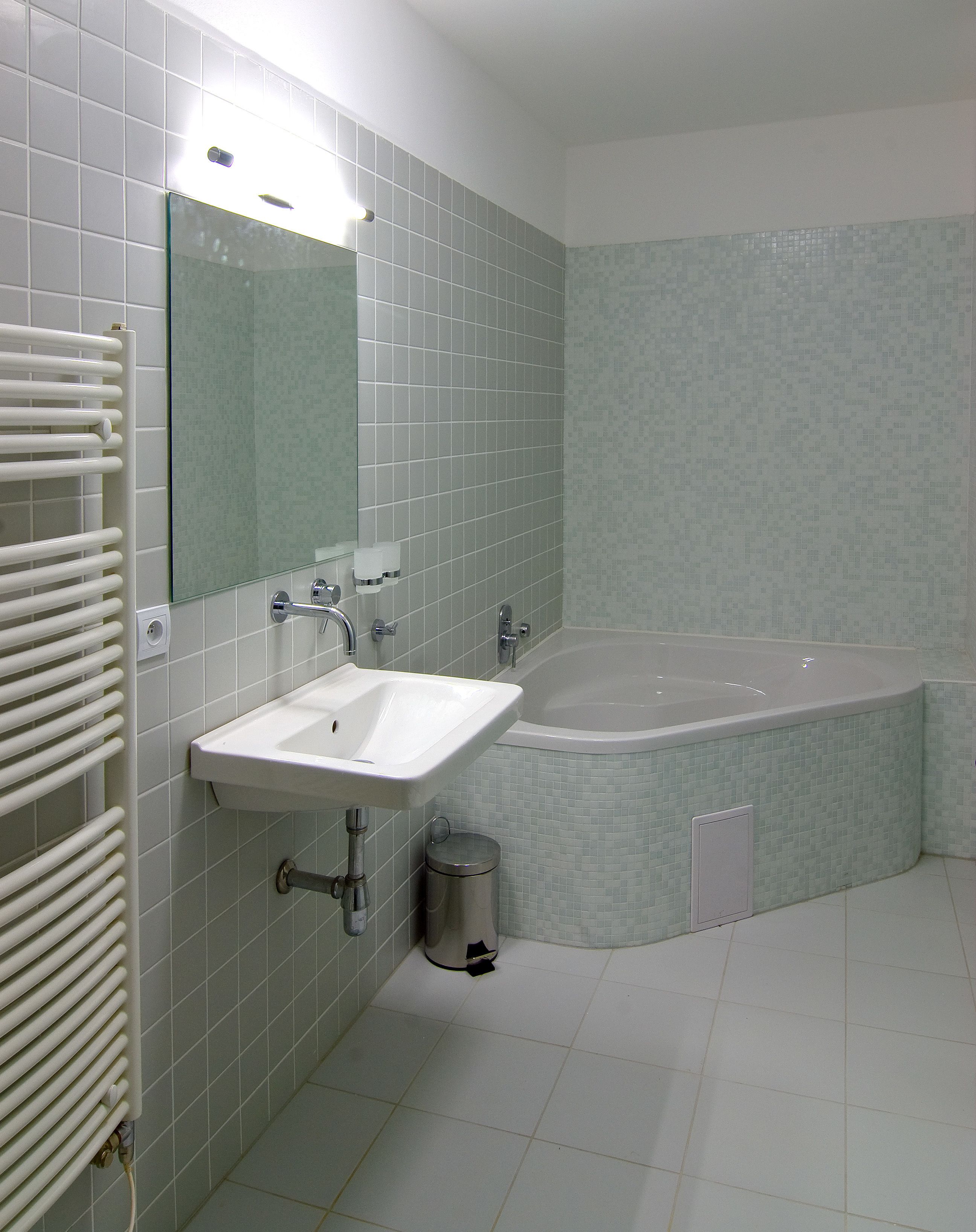 A bathroom with a sink, mirror, and bathtub.