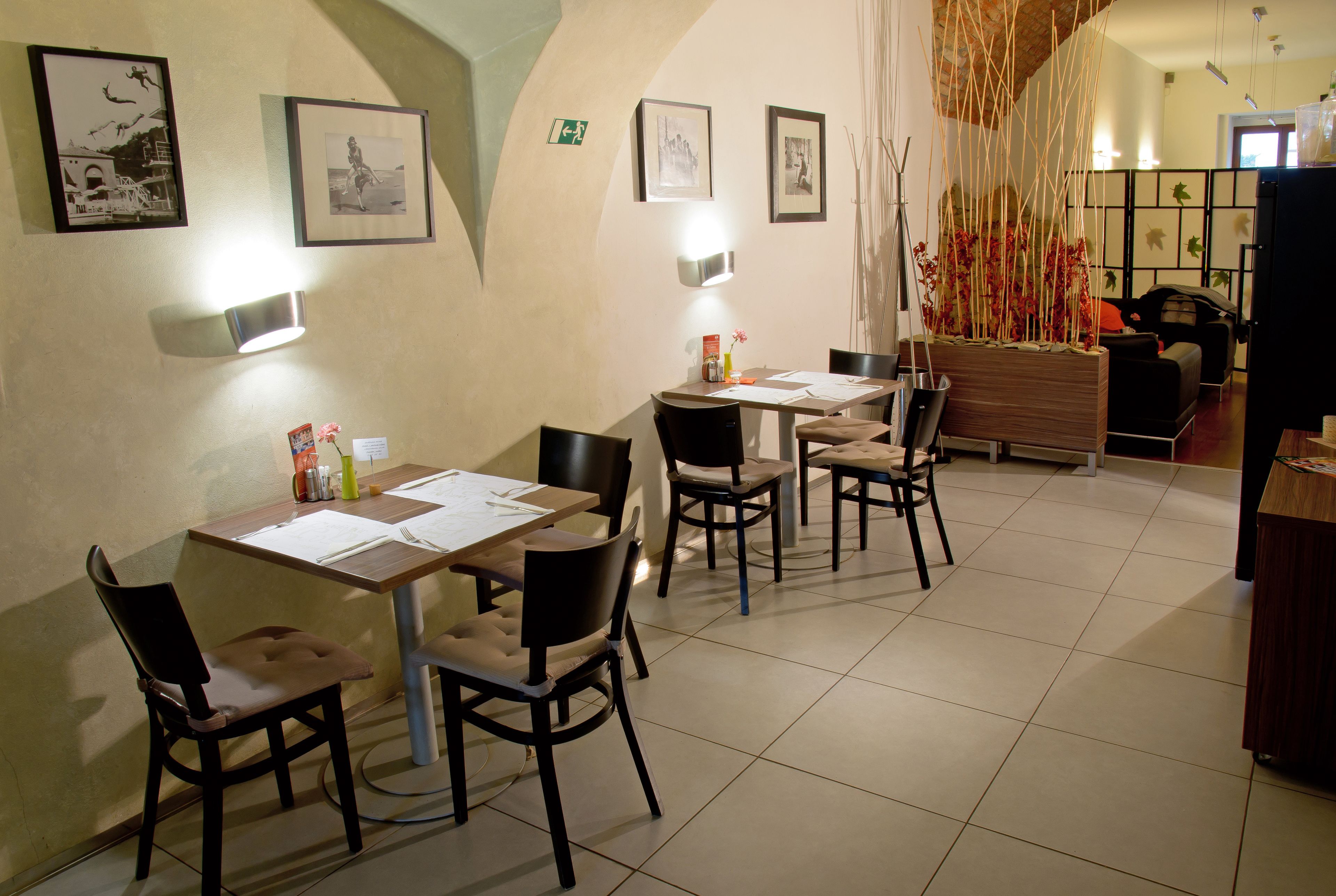A dining area with tables and chairs, framed pictures on the walls, and a decorative plant.