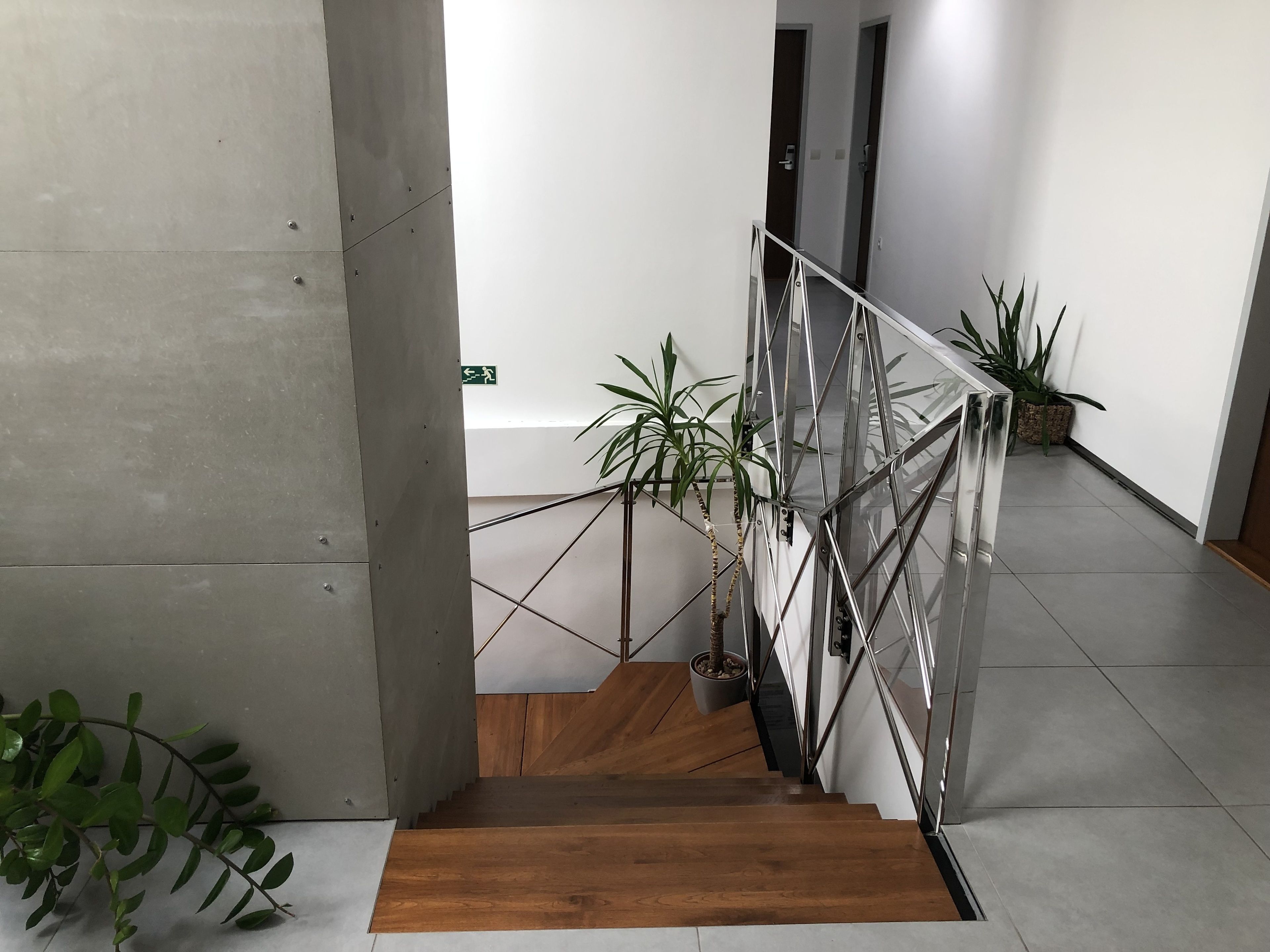 Una escalera con barandillas de metal, escalones de madera y plantas en macetas.