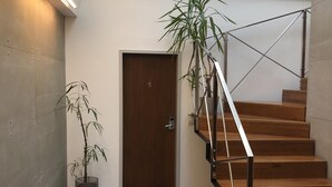 Una escalera moderna con escalones de madera y barandillas de metal, que conduce a una puerta con el número 1.