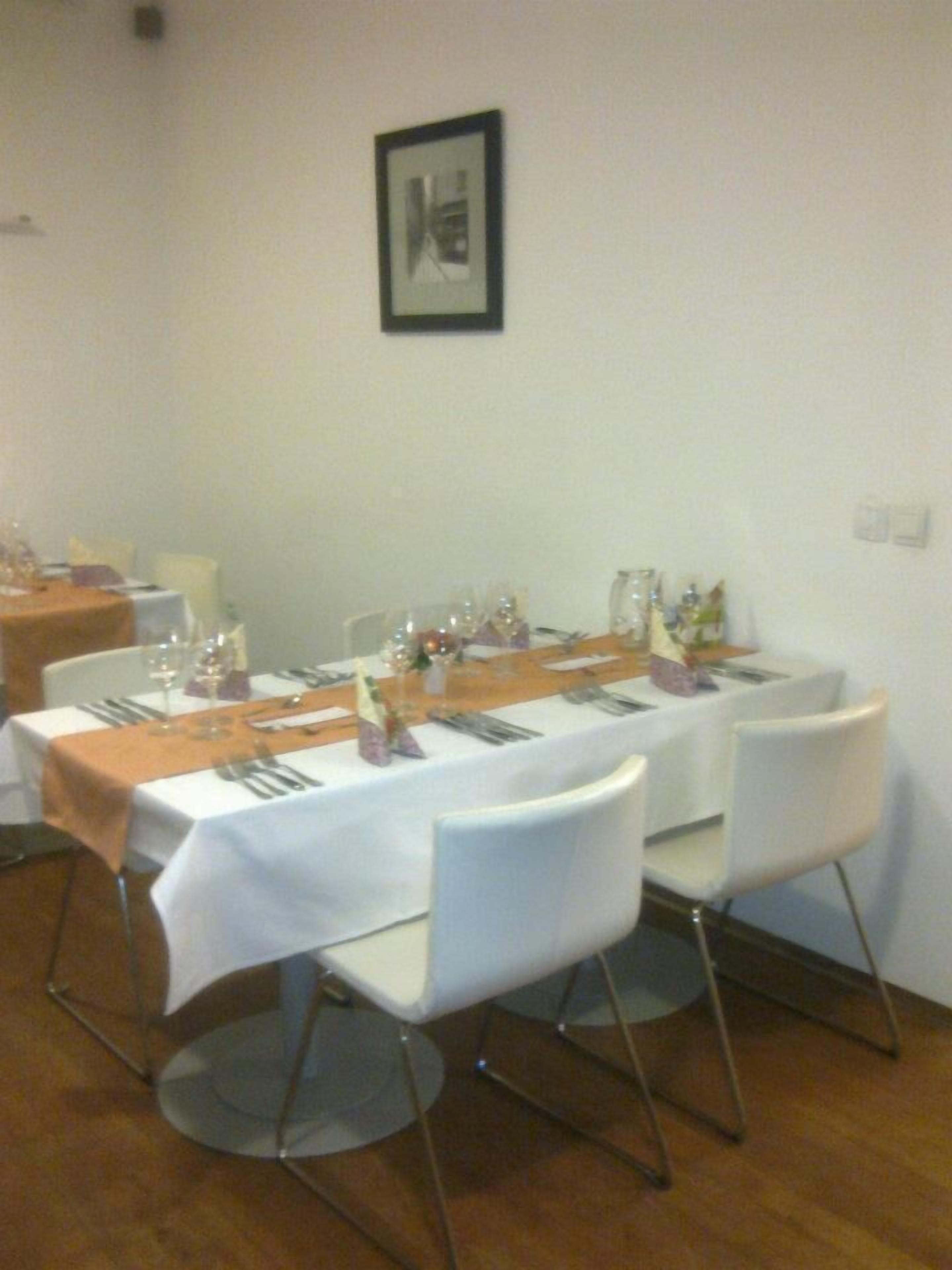A dining area with a long table set for a meal, white chairs, and a framed picture on the wall.