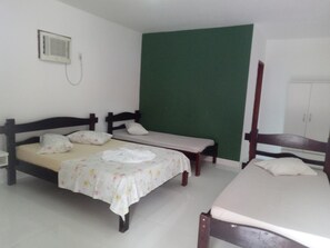 A room with two beds, a green wall, a white cabinet, and a wall-mounted heater.